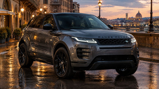 Range Rover Evoque grigio scuro con tetto e calotte nere parcheggiato su una strada bagnata di una città italiana al tramonto